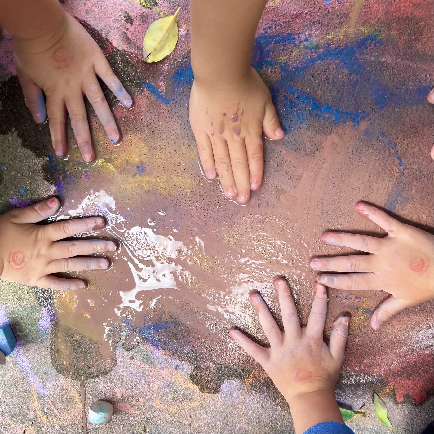 Children's hands creating chalk art together