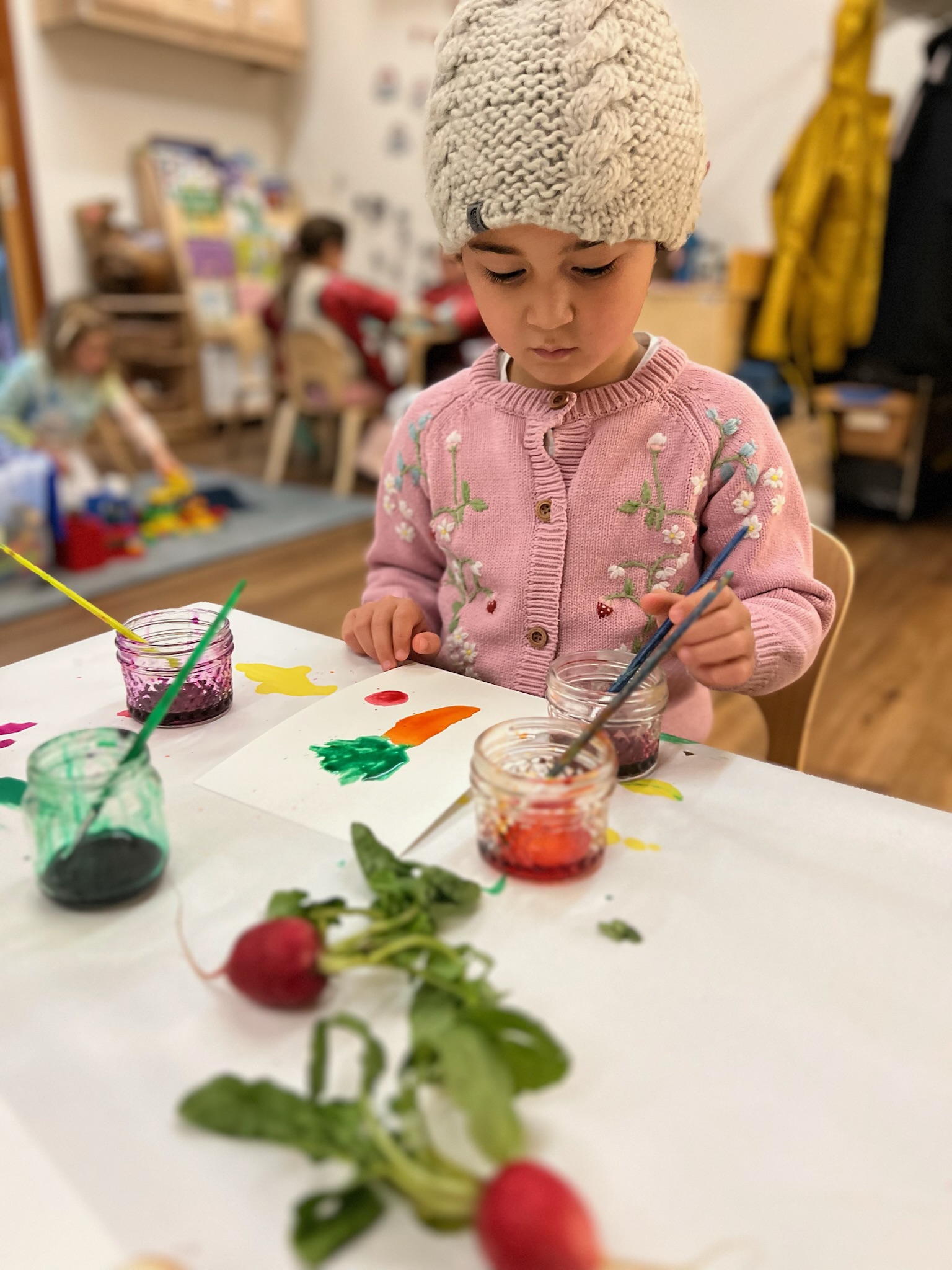 Child painting with fresh vegetables at The Ross Preschool